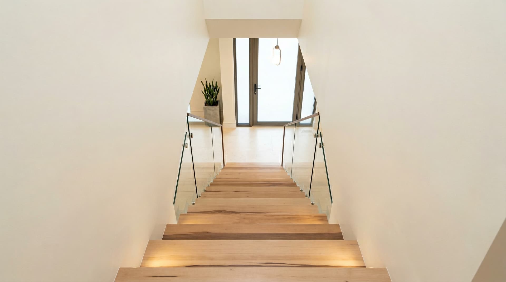 Una elegante escalera de madera de haya de tono claro y vetas finas integrada en un salón moderno, destacando la robustez del material y un diseño de líneas limpias que aporta luminosidad a la estancia.