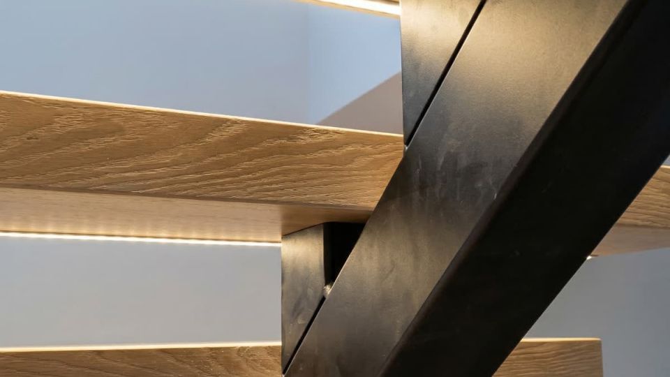 Detalle técnico de peldaños flotantes de madera con sistema de luz LED oculta.